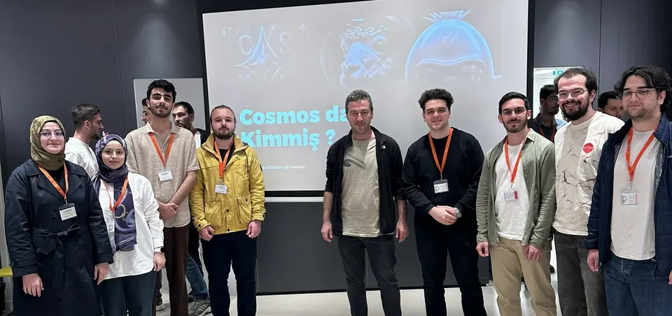 Group photo of about a dozen people in front of a presentation slide that reads "Cosmos da Kimmiş?"